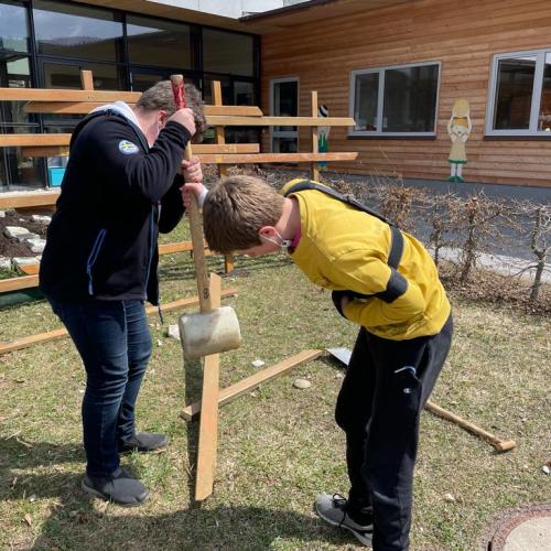 zwei Buben mit Werkzeug vor dem Gartenzaun 